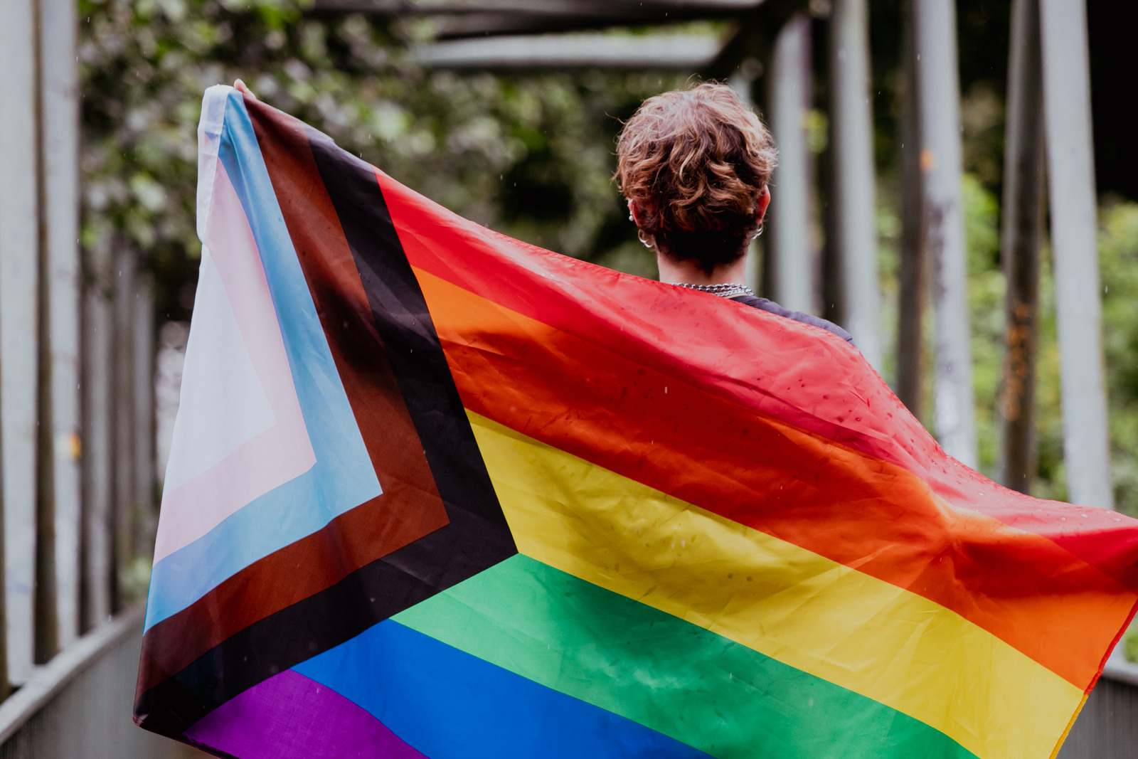 Person holding a pride progress flag outdoors